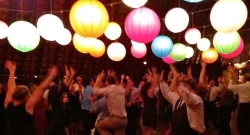 Guests with hands in air and cool, funky lights hanging from ceiling