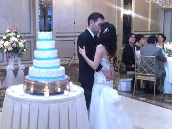 Bride and Groom share a kiss by the wedding cake at the Surf club in New Rochelle NY