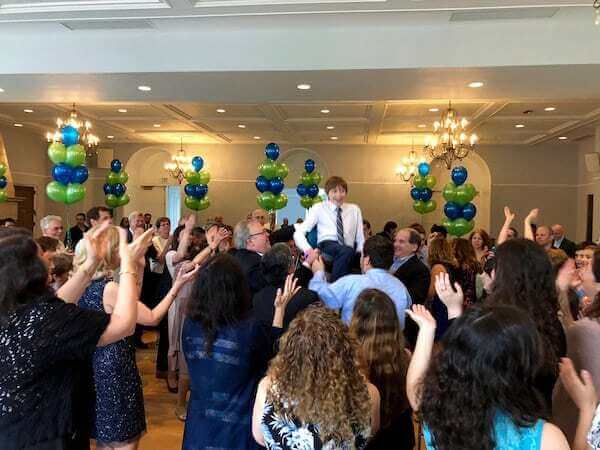 Bar Mitzvah boy lifted on chair during Hora